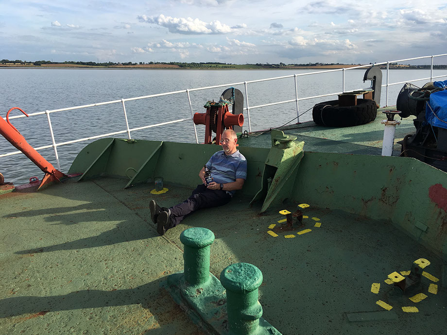Keith, G6NHU sitting on the front of the ship with a bottle of beer, shortly after GB5RC went on air from Ross Revenge, home of Radio Caroline.
